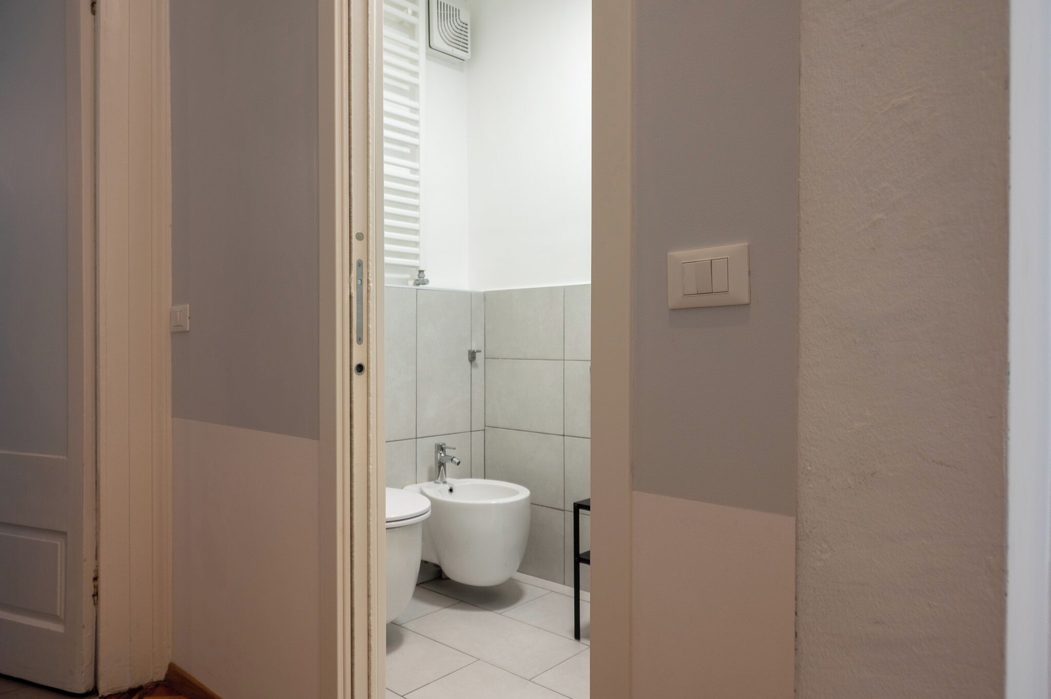Ein Badezimmer mit Toilette, Bidet und einem schwarzen Metallstuhl.