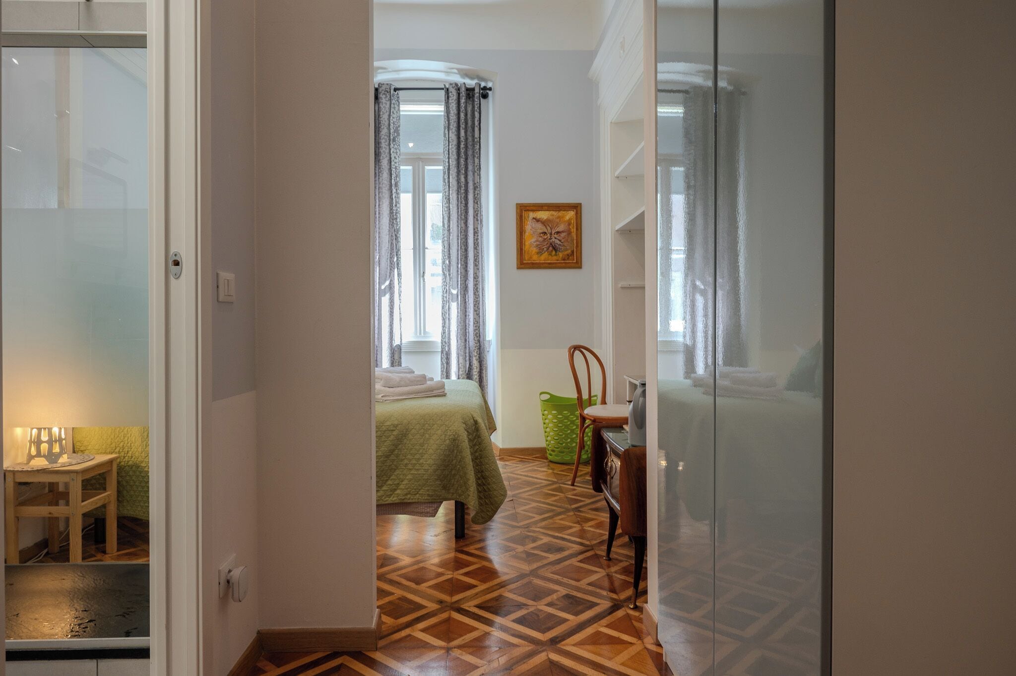 A room with a bed, a chair, a table, and a window with curtains.