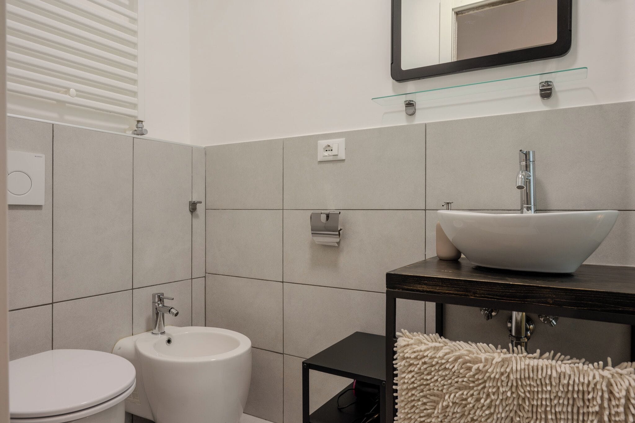 A modern bathroom with a white sink, bidet, and toilet.