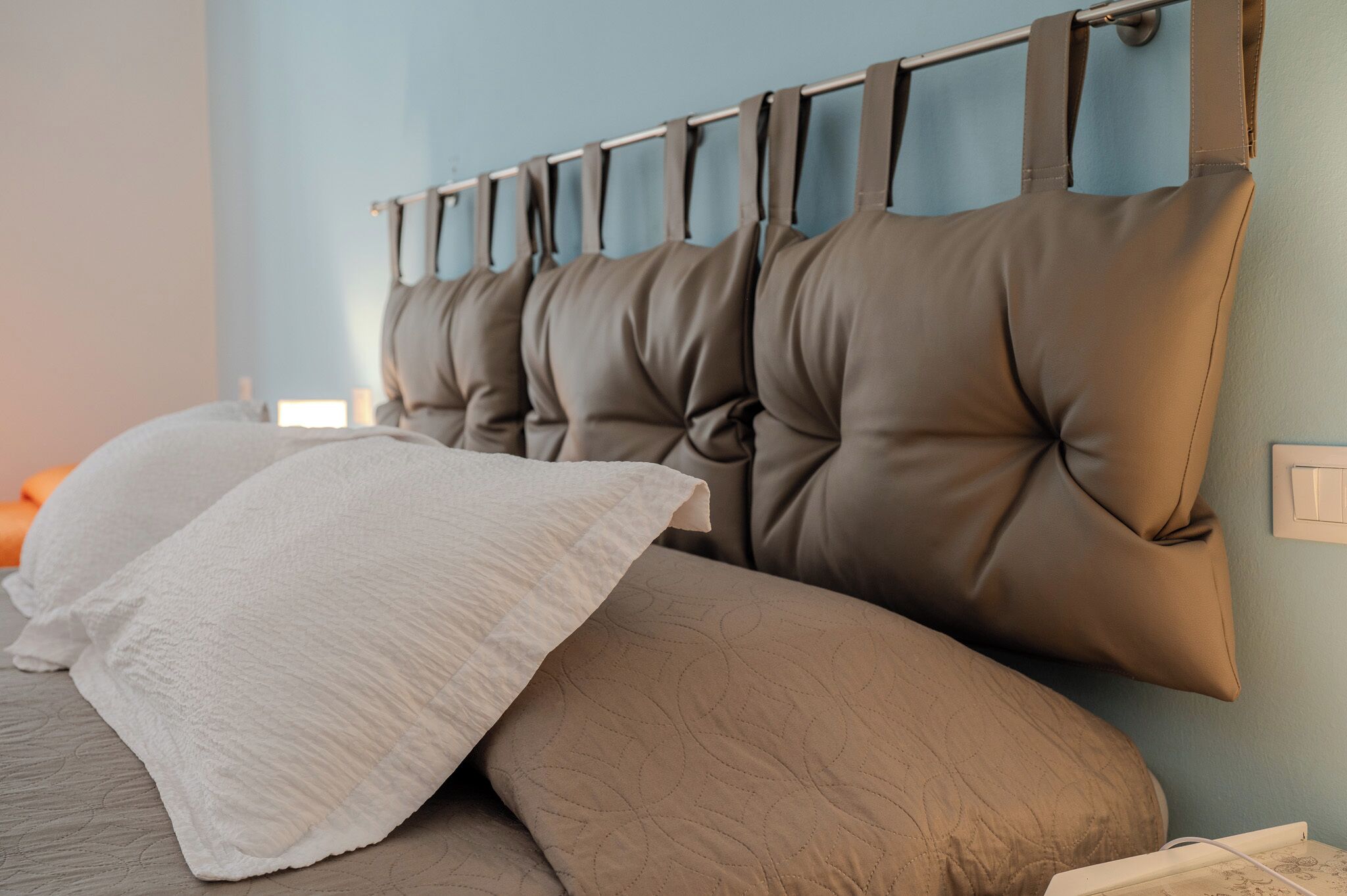 A bed with a headboard, pillows, and a bedside table with a lamp.