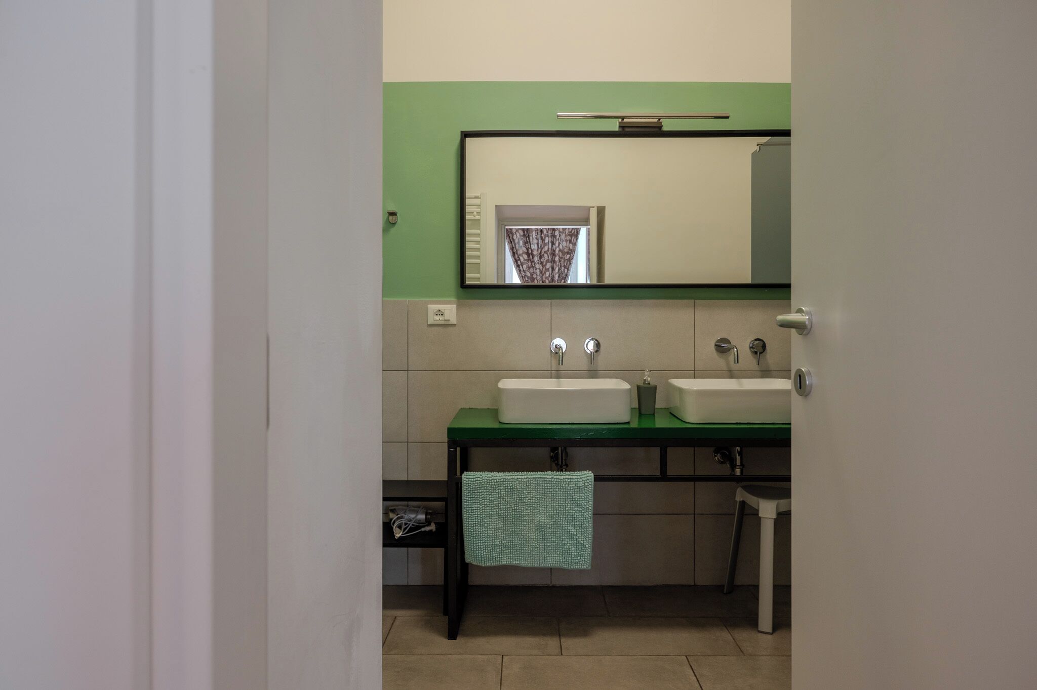 A bathroom with two sinks, a mirror, and a towel hanging on the wall.