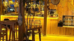 Un restaurant chaleureux, décoré de bois, avec une plante au centre et un comptoir où est affiché le menu.
