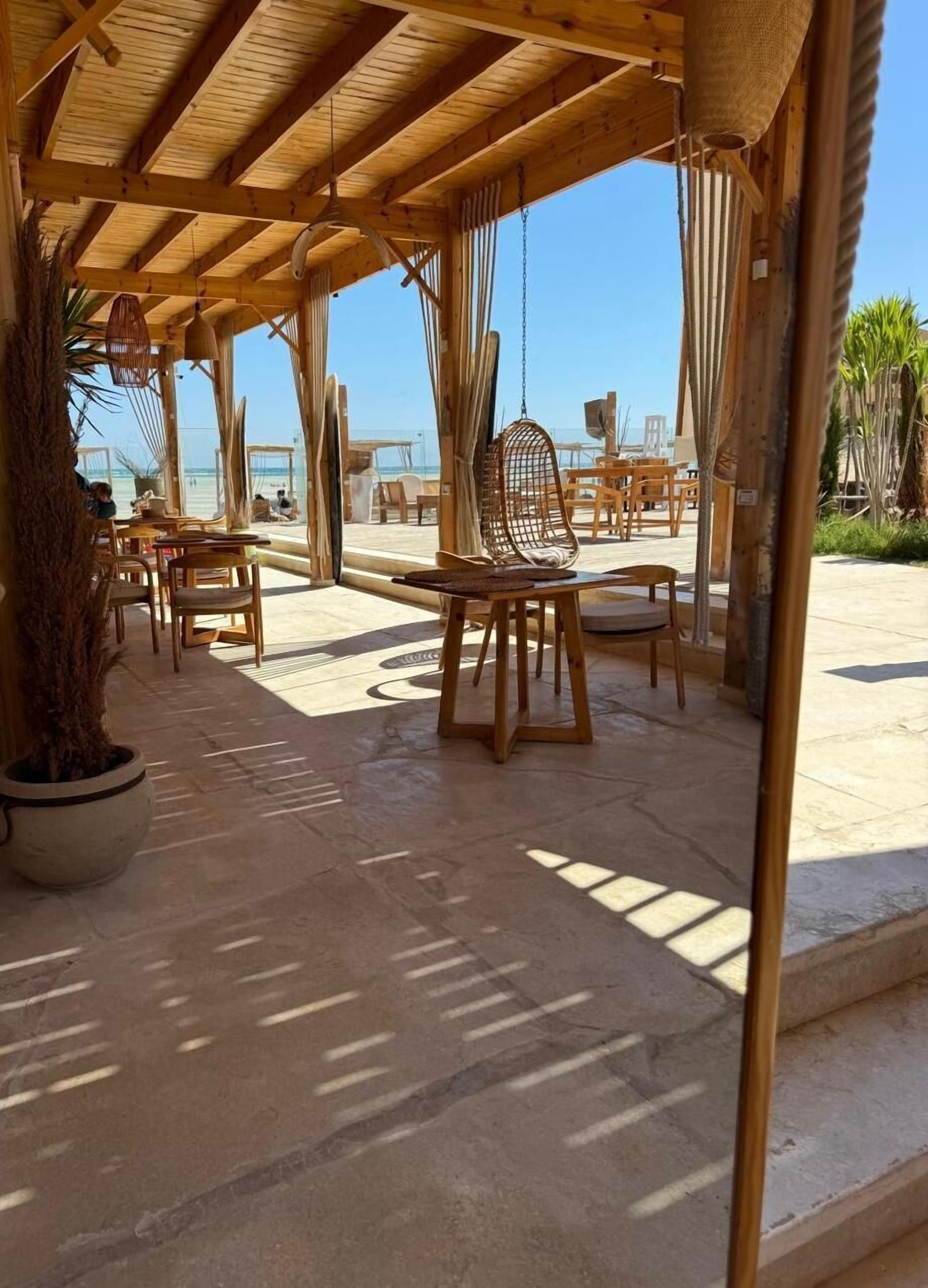Un espace extérieur aménagé avec du mobilier en bois et offrant une vue sur la plage.