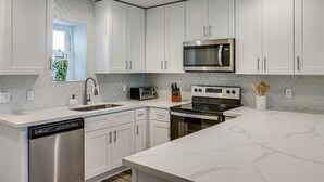 Une cuisine moderne avec des meubles blancs, un lave-vaisselle en acier inoxydable, un four à micro-ondes et une cuisinière.