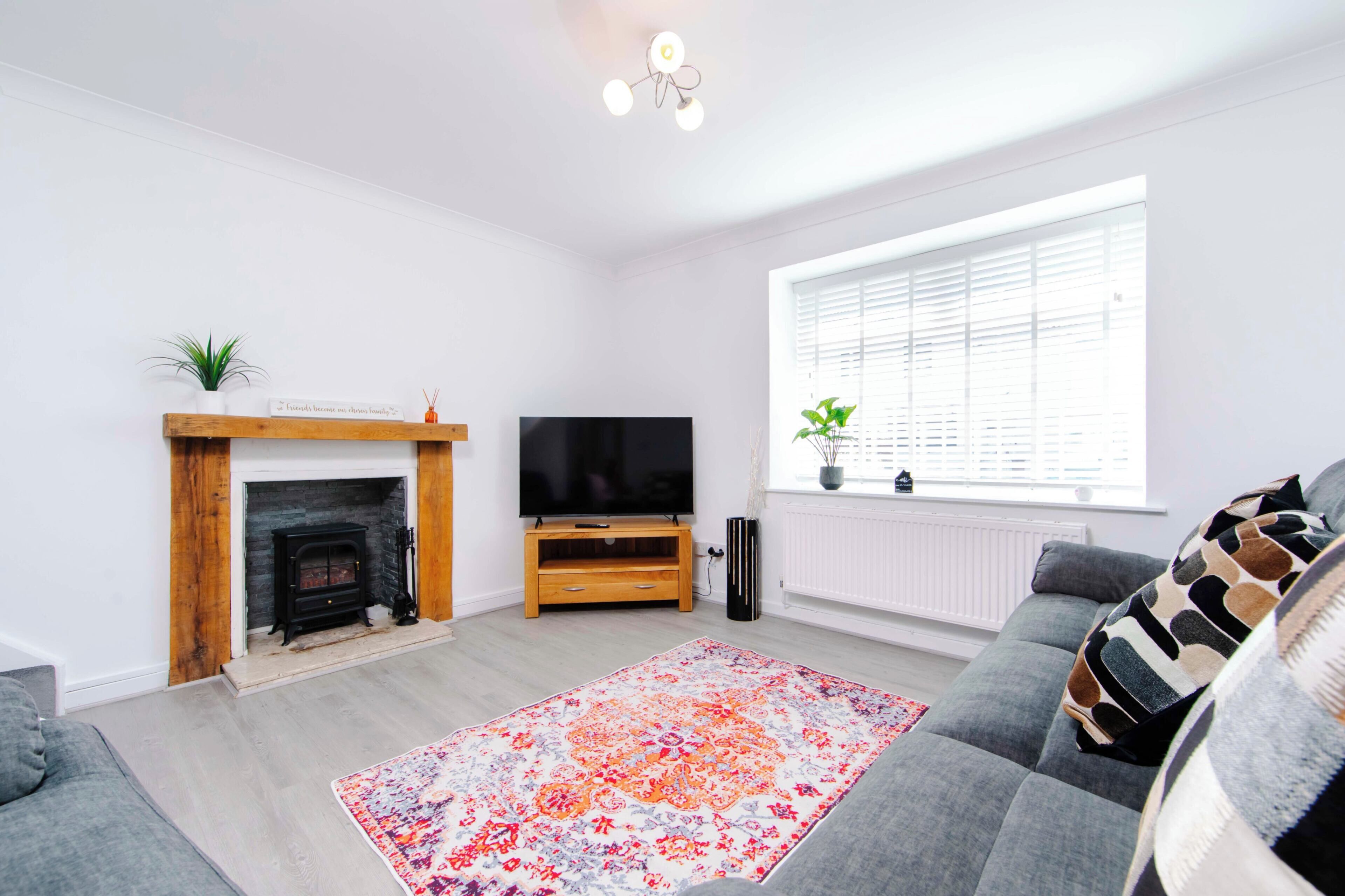 A modern living room with a fireplace, a flat-screen TV, a sofa, and a large window.
