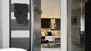 Une salle de bain moderne avec une douche à l’italienne en verre, une baignoire blanche et un porte-serviettes avec une serviette foncée.