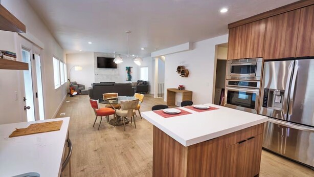 A modern kitchen with a central island, built-in appliances, and a dining area with a round table and chairs. - 3 Bedroom, 4 bed/3 Bath, Close to Mountains, Downtown and Airport (Midvale)