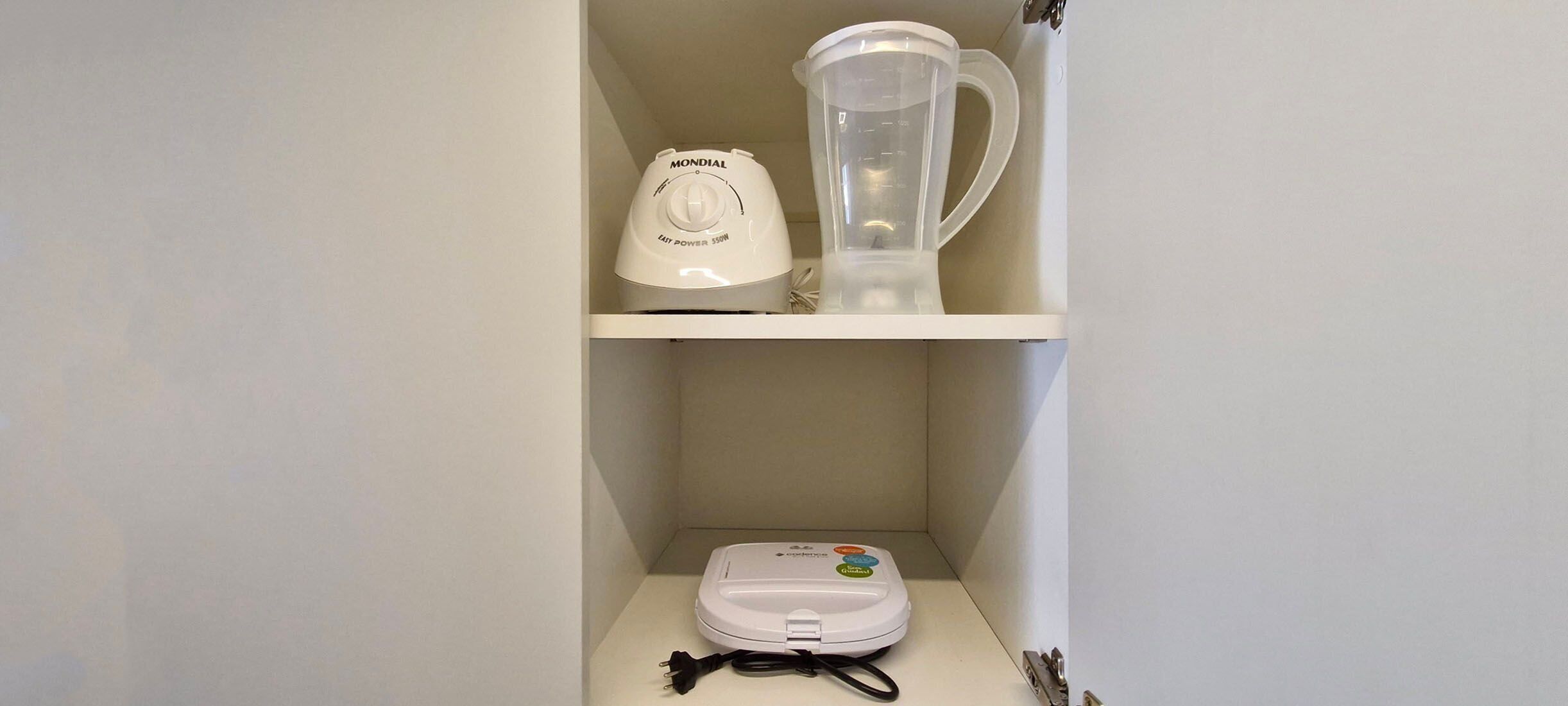 Une cuisine avec un plan de travail blanc, un mixeur, une bouilloire et une machine à café.