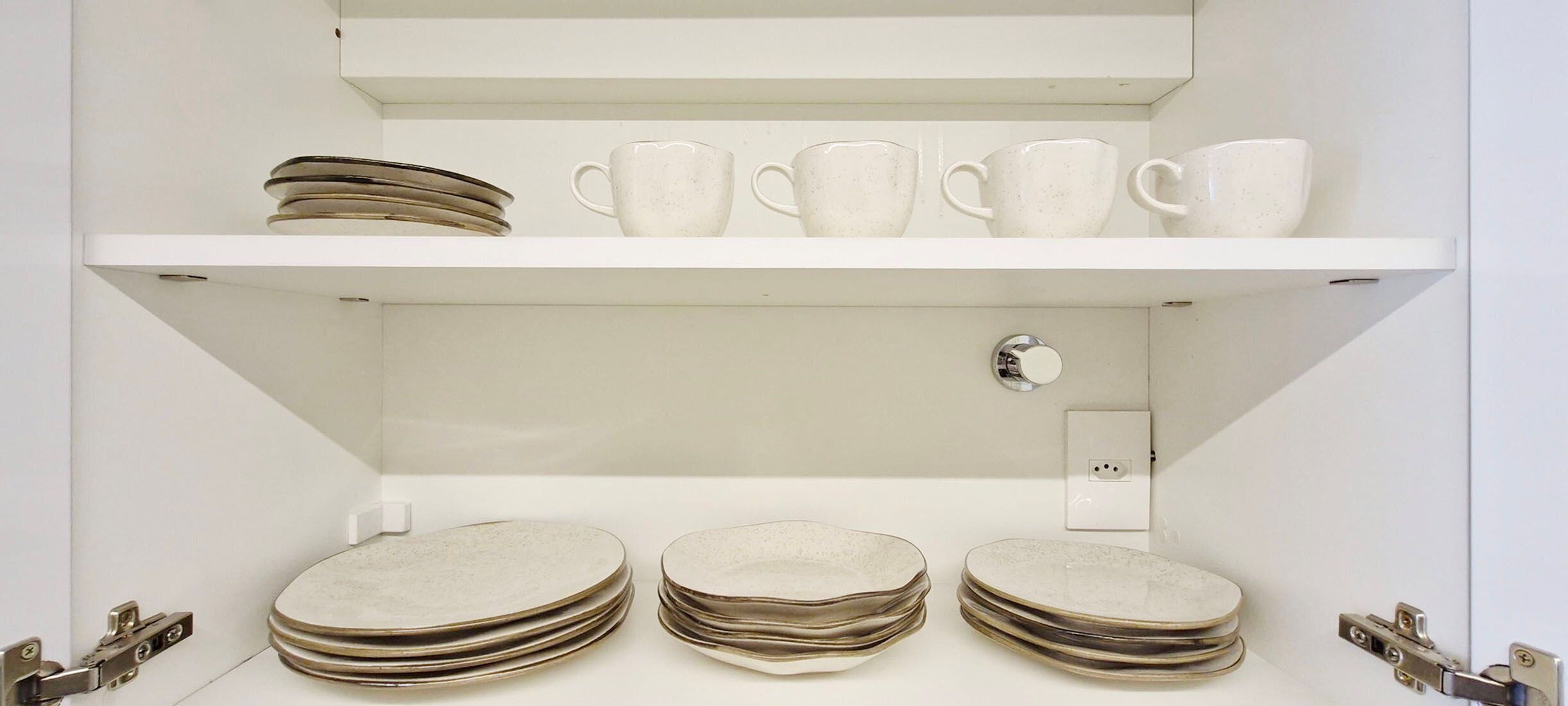 Estant blanc amb plats apilats i tasses blanques.