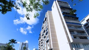 Un hôtel à plusieurs étages au design moderne, doté de balcons à chaque niveau et offrant une vue dégagée sur le ciel.