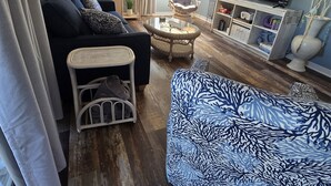 A living room with a sofa, armchair, and a TV on a stand.