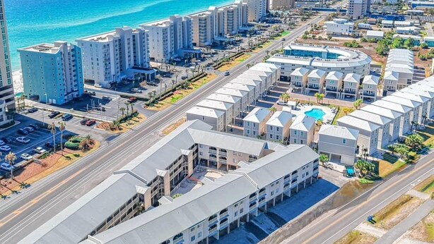 A coastal urban area with high-rise buildings, a marina, and a clear view of the ocean.