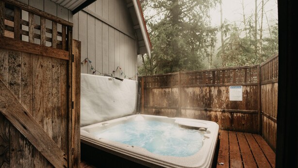 A hot tub in a wooden outdoor area with a wooden fence and trees in the background. - 52mbr - Hot Tub - Pets Ok - Generator - Wifi (Deming)