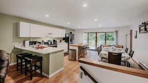 A modern kitchen with white cabinets, a central island with stools, and a dining area with a table and chairs. - 52mbr - Hot Tub - Pets Ok - Generator - Wifi (Deming)