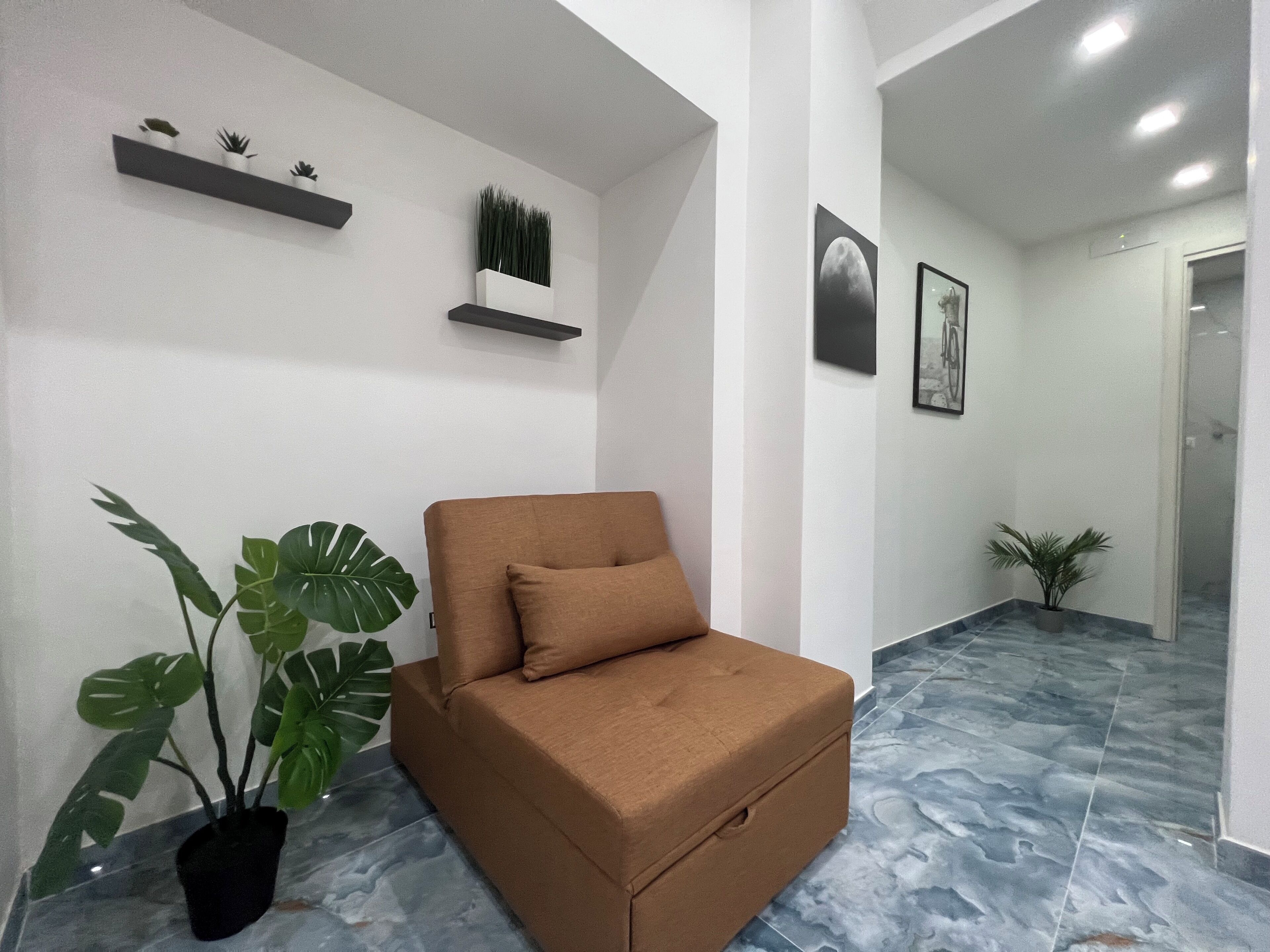Un interior moderno con un sofá marrón, plantas en macetas y piso de baldosas.