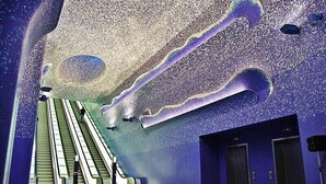 Un espace intérieur doté d’escalators, d’un grand plafond décoratif et de deux portes.