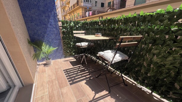 Un petit espace extérieur aménagé en patio, avec un sol carrelé, une table en bois, deux chaises et une plante en pot.