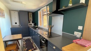 A compact kitchen with a microwave, stove, and sink. - Les étoiles du Périgord vert (Gîte ALTAÏR) (Mialet)