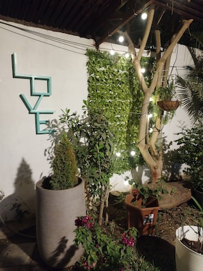 A garden area with a wall-mounted sign, potted plants, and hanging lights.