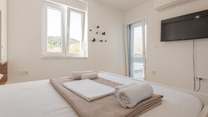 Habitación de hotel con una cama grande, un televisor de pantalla plana montado en la pared y una ventana con vistas al exterior.