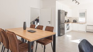 Una cocina moderna con refrigerador, estufa y pileta. Hay un comedor con una mesa y sillas de madera.