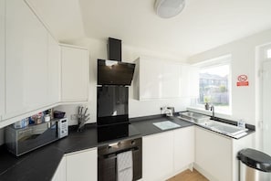 Eine moderne Küche mit weißen Schränken, einer schwarzen Arbeitsplatte, einem Einbauofen und einem Fenster mit Blick.