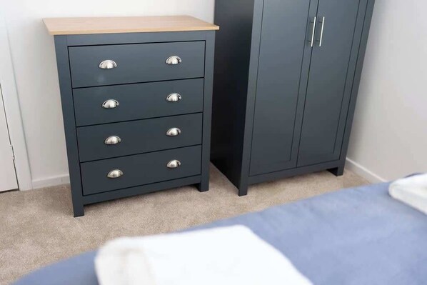 A bedroom with a bed, a dark-colored dresser with drawers, and a wardrobe with two doors.