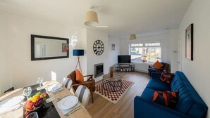 A modern living room with a dining area, a sofa, a TV, and a fireplace. - Derry House - spacious 3 bed house with driveway (Aberdeen)