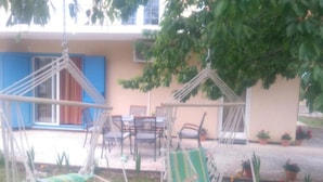A patio with two hanging chairs, a table, and chairs. - Villa Anita (Unesic)