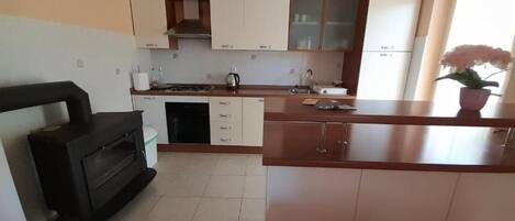 A compact kitchen with white cabinets, a black stove, and a wooden countertop.
