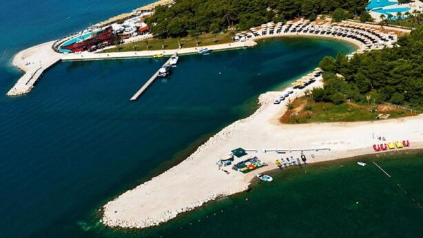 An aerial view of a coastal resort with a marina, beach, and pool area. - Villa Anita (Unesic)
