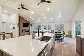Una cocina moderna con una isla grande, electrodomésticos integrados y un comedor con mesa y sillas.