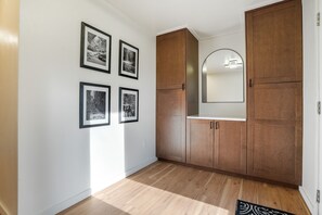 Un couloir avec des armoires en bois, un mur blanc et quatre tableaux encadrés.