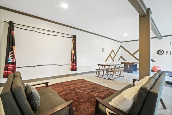 A modern living room with a brown rug, two sofas, a table, and a wall with geometric patterns.