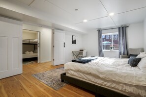 A modern bedroom with a large bed, a desk, and a bunk bed in the adjacent room. - The Haven @ Hocking | Luxury Retreat, Hot Tub (Rockbridge)