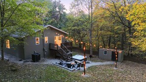 A cabin with a deck, outdoor seating, and a hot tub.