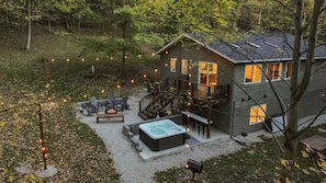 Una casa de dos pisos con un porche, mobiliario exterior y un jacuzzi.