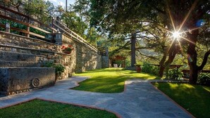 A stone pathway leading to a gazebo in a garden with a stone wall and greenery. - Private villa with pool, hot tub and garden in the Tuscan countryside (Castel Focognano)