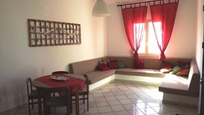 A living room with a dining area, a sofa, and a decorative wall piece.