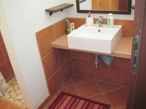 Ein Badezimmer mit einem weißen Waschbecken, einem Spiegel und einem Handtuchhalter.