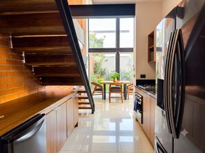 Een moderne keuken met houten kastjes, een roestvrijstalen koelkast en een eethoek met een tafel en stoelen.