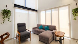 Ein modernes Wohnzimmer mit einem grauen Sofa, einem Holzstuhl und einem kleinen Holztisch.