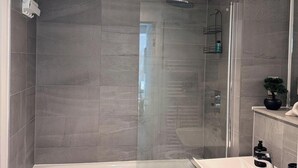A modern bathroom with a glass-enclosed shower, a white bathtub, and a sink with a mirror. - City Centre - 2-bed High Rise Apartment - Sleeps 4 (Manchester)