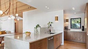 Une cuisine moderne dotée d’un grand îlot central, de meubles en bois et d’un lave-vaisselle encastré.