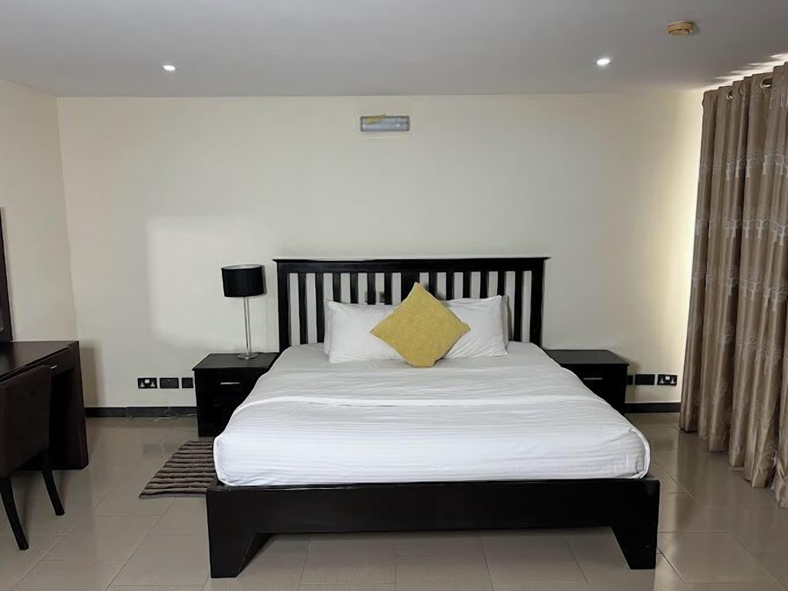A modern hotel room with a large bed, a desk, and a chair.