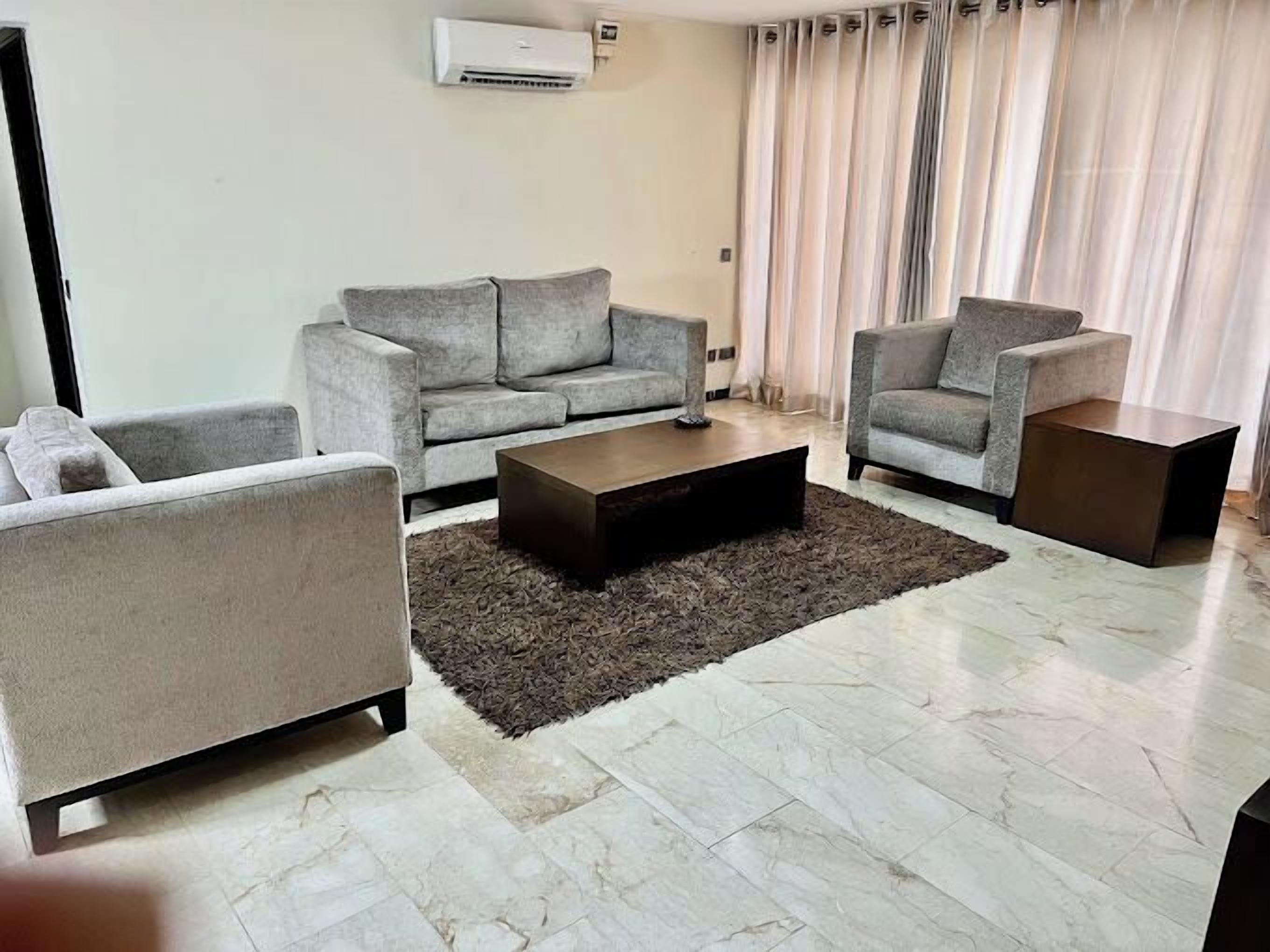 A modern living room with a grey sofa set, a coffee table, and a rug.