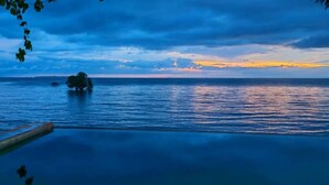 Ein Blick auf ein ruhiges Meer bei Sonnenuntergang, mit einer entfernten Küste und einer kleinen Insel.