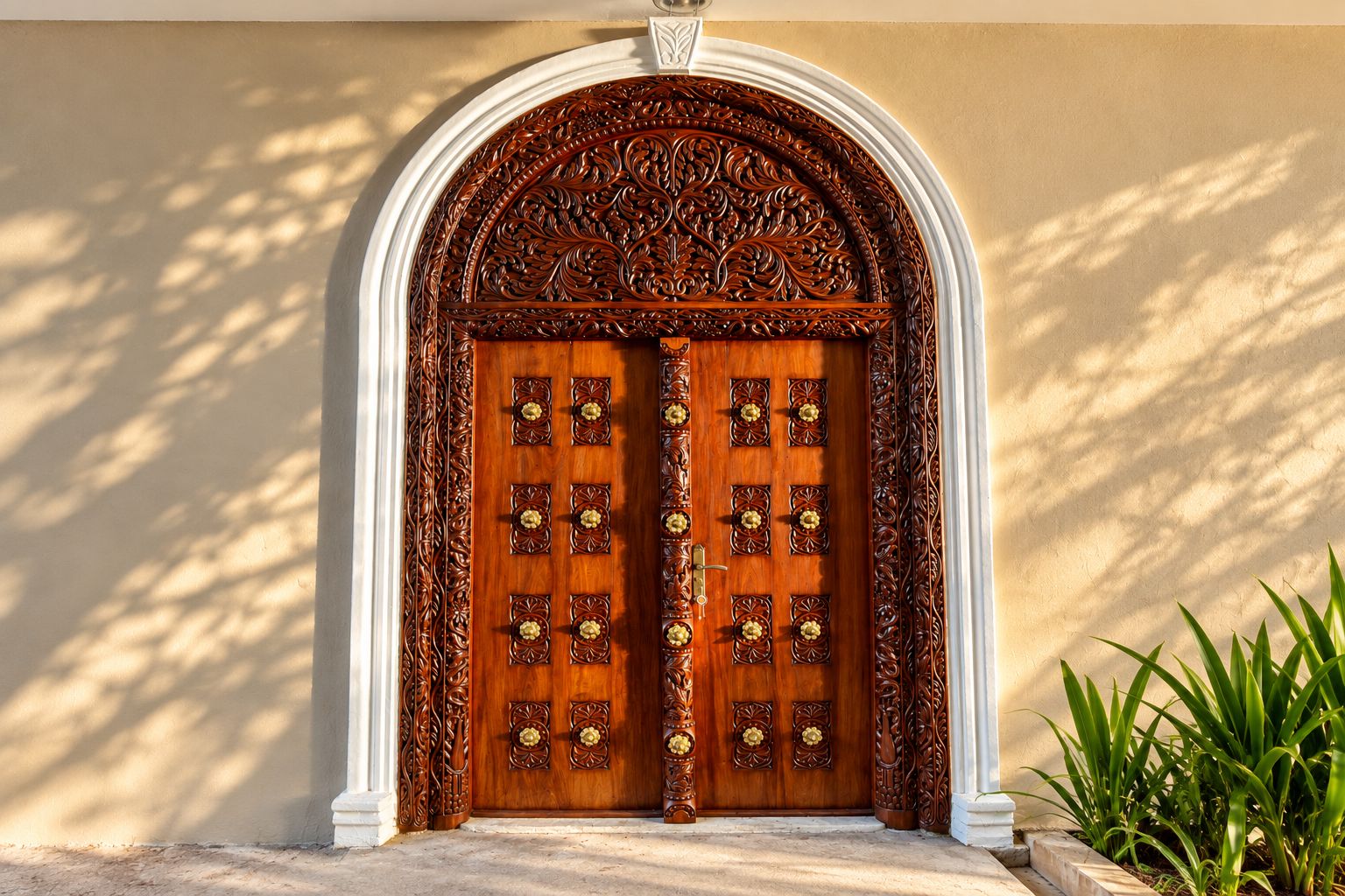 A double wooden door with intricate carvings and a white archway.