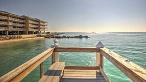 A wooden deck leading to a beach with a hotel in the background.