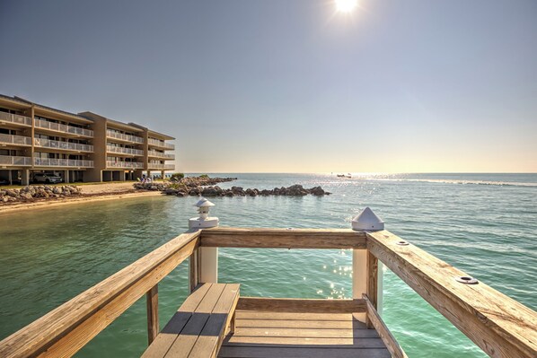 A wooden deck leading to a beach with a hotel in the background. - Family friendly 2bedroom+bunkroom/2.5bath oceanfront condo (Key Colony Beach)